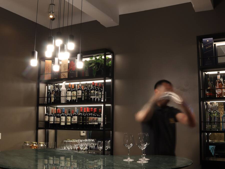 A bar area with a round table, chairs, and shelves of bottles.