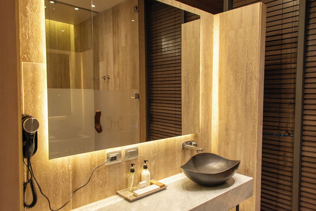 Un baño moderno con un espejo grande, un lavabo y un secador de pelo montado en la pared.