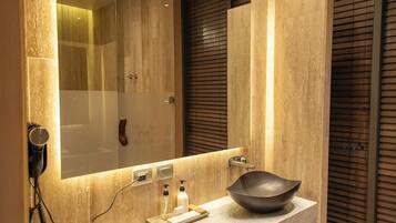 Un baño moderno con un espejo grande, un lavabo y un secador de pelo montado en la pared.