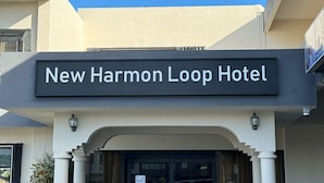 L’extérieur du nouvel hôtel New Harmon Loop présente une entrée bien dégagée, des colonnes et des plantes en pot.