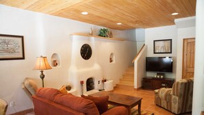 A living room with a fireplace, sofa, television, and a staircase.