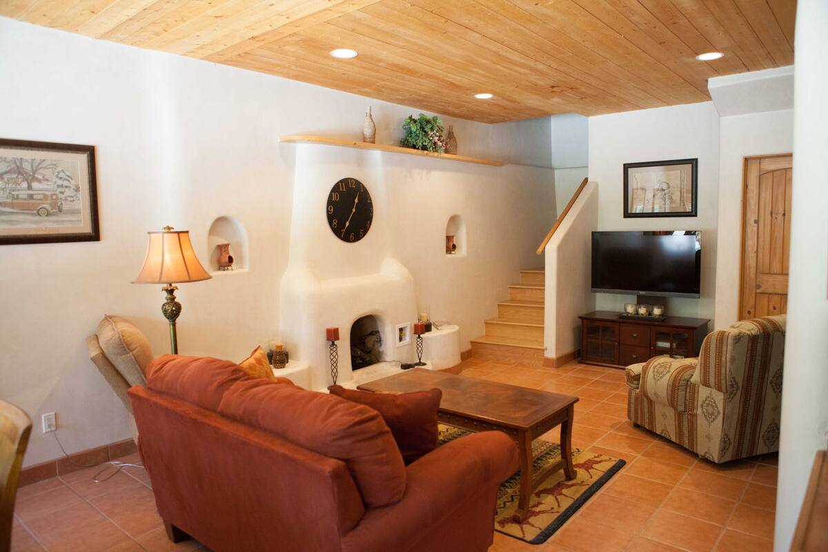 A living room with a fireplace, sofa, television, and a staircase.
