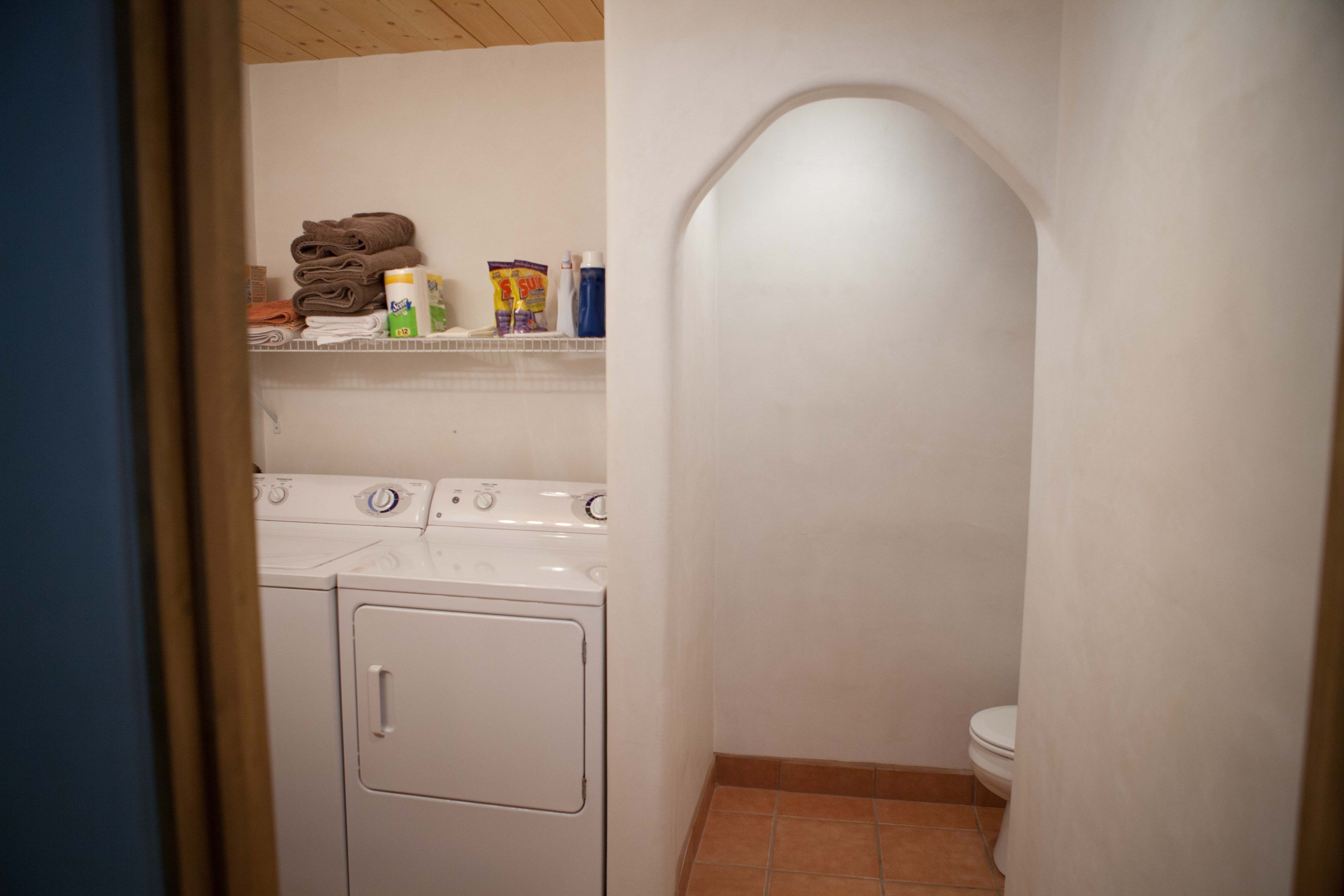 A compact laundry room with a washing machine, dryer, and a small shelf with toiletries.
