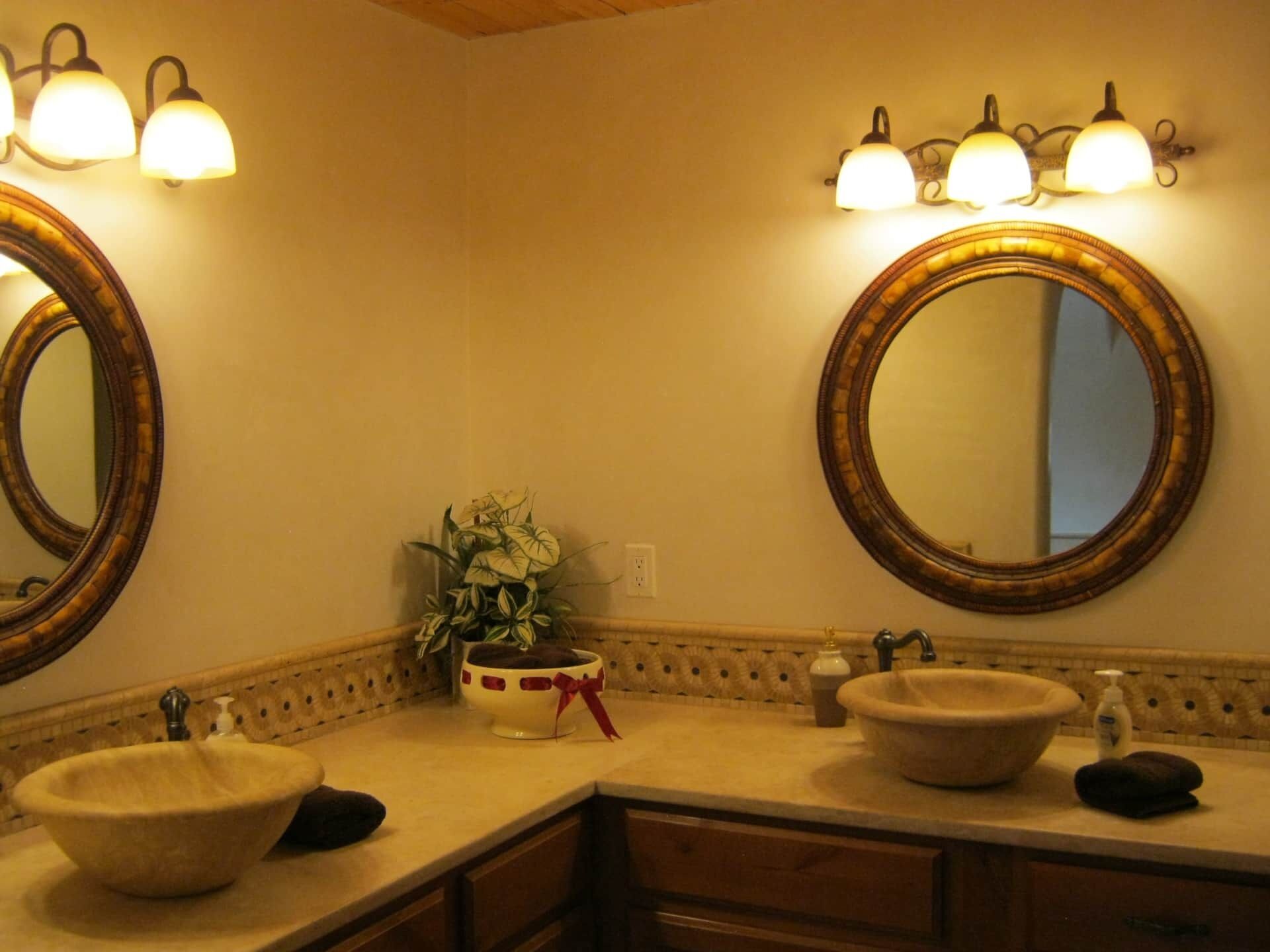 Un baño con dos lavamanos, un espejo e iluminación en la pared.