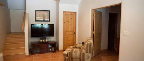 Una sala de estar con una escalera de madera, un televisor, un sofá y una mesa de centro.