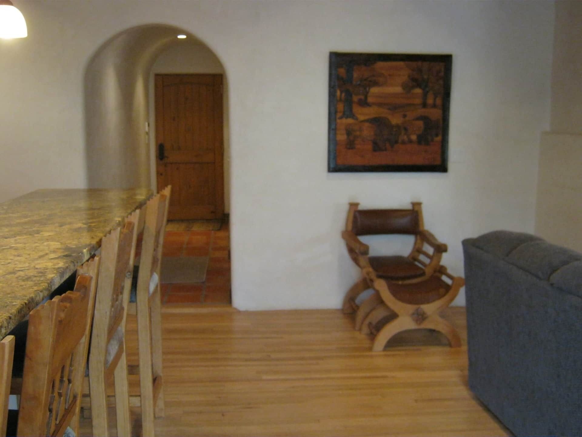 A dining area with a wooden table and chairs, a wooden bench, and a gray sofa.