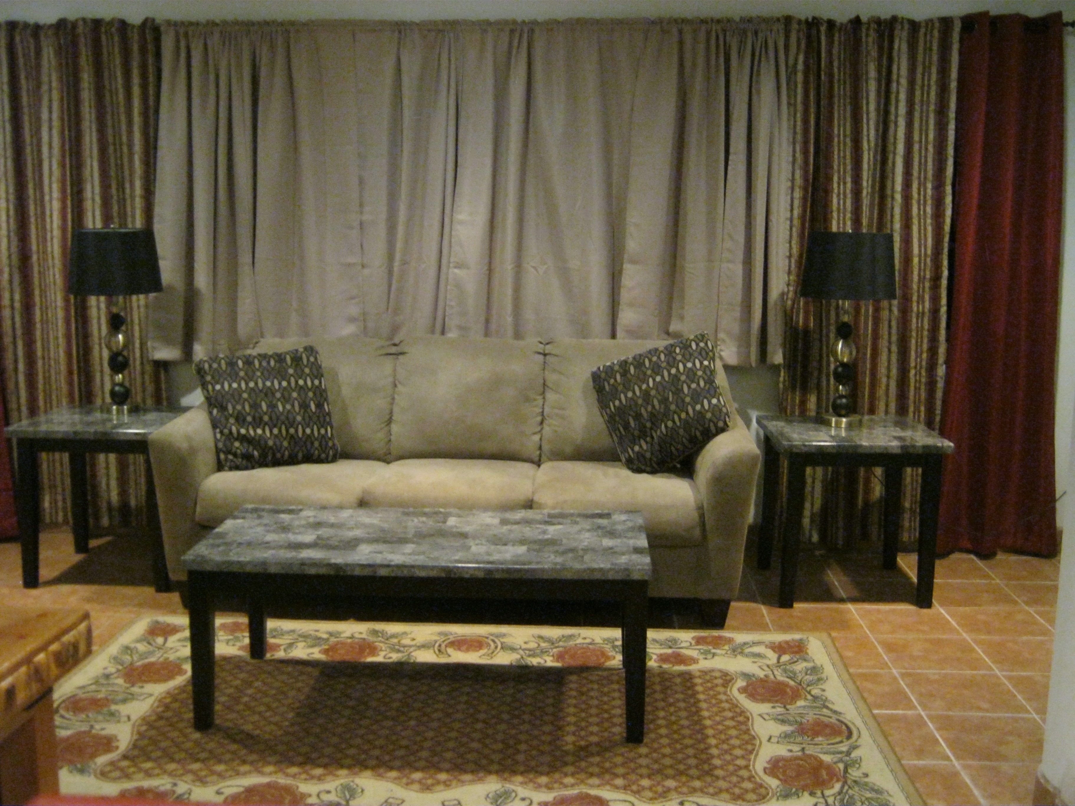 A living room with a sofa, two side tables with lamps, and a patterned rug.