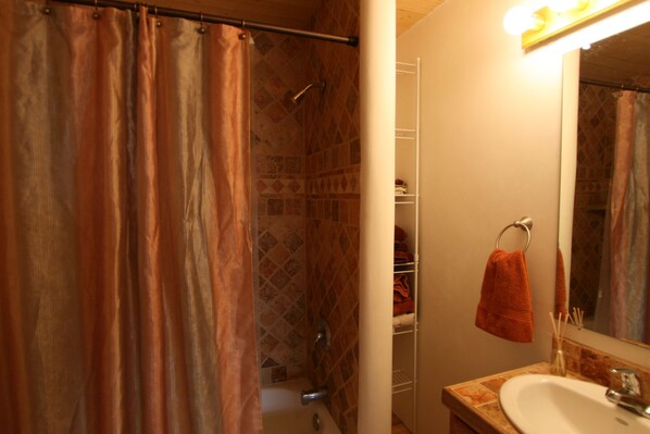 Un baño con cortina de ducha, lavabo, espejo y toallero.
