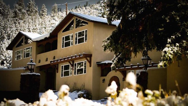 A two-story building with a symmetrical facade, large windows, and a covered porch area.