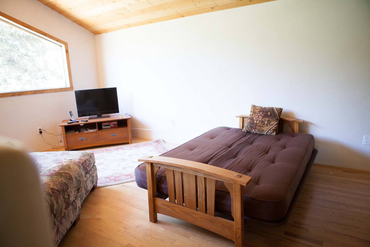 A bedroom with a bed, a television, and a wooden headboard.