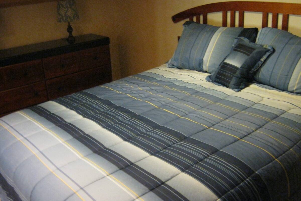 A bed with a striped bedspread and two pillows.