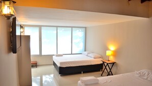 A hotel room with two beds, a bench, a lamp, and a large window. - Hotel Casa La Fleur (Medellín)