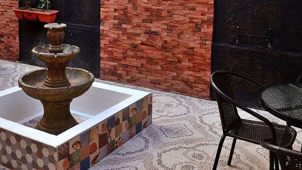 A courtyard with a fountain, outdoor seating, and potted plants against a brick wall. - Hotel Casa La Fleur (Medellín)