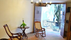 A room with two rocking chairs, a small table with a vase, and a balcony with a railing. - Hotel Casa La Fleur (Medellín)