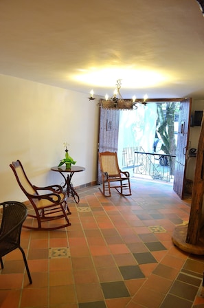 Relax in this inviting room with a checkered tile floor, two comfortable rocking chairs, and a charming balcony with a view.