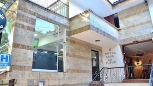 A hotel entrance with a stone facade, a visible staircase, and a sign indicating the hotel's name. - Hotel Casa La Fleur (Medellín)