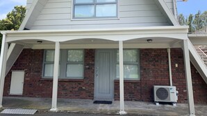 A two-story house with a covered porch, a brick facade, and a central chimney. - Colonial Motel (Papakura)