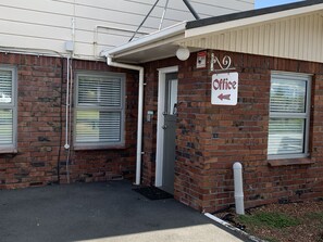 A brick building with a sign indicating an office. - Colonial Motel (Papakura)