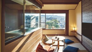 A modern room with a large window, a small round table, and traditional cushions. - Laforet Ito Onsen Yunoniwa (Ito)