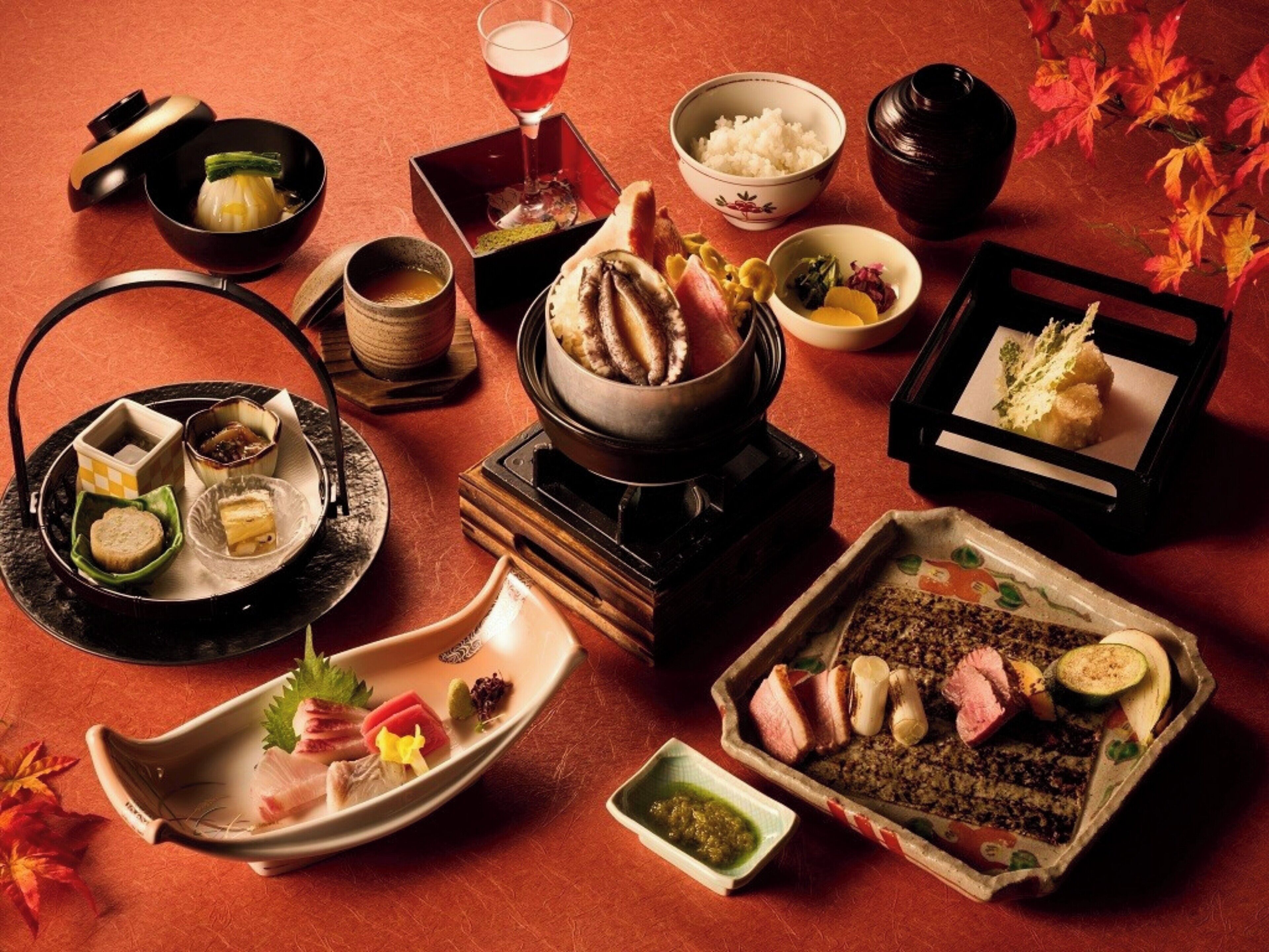 A variety of Japanese dishes arranged on a table with a red background.