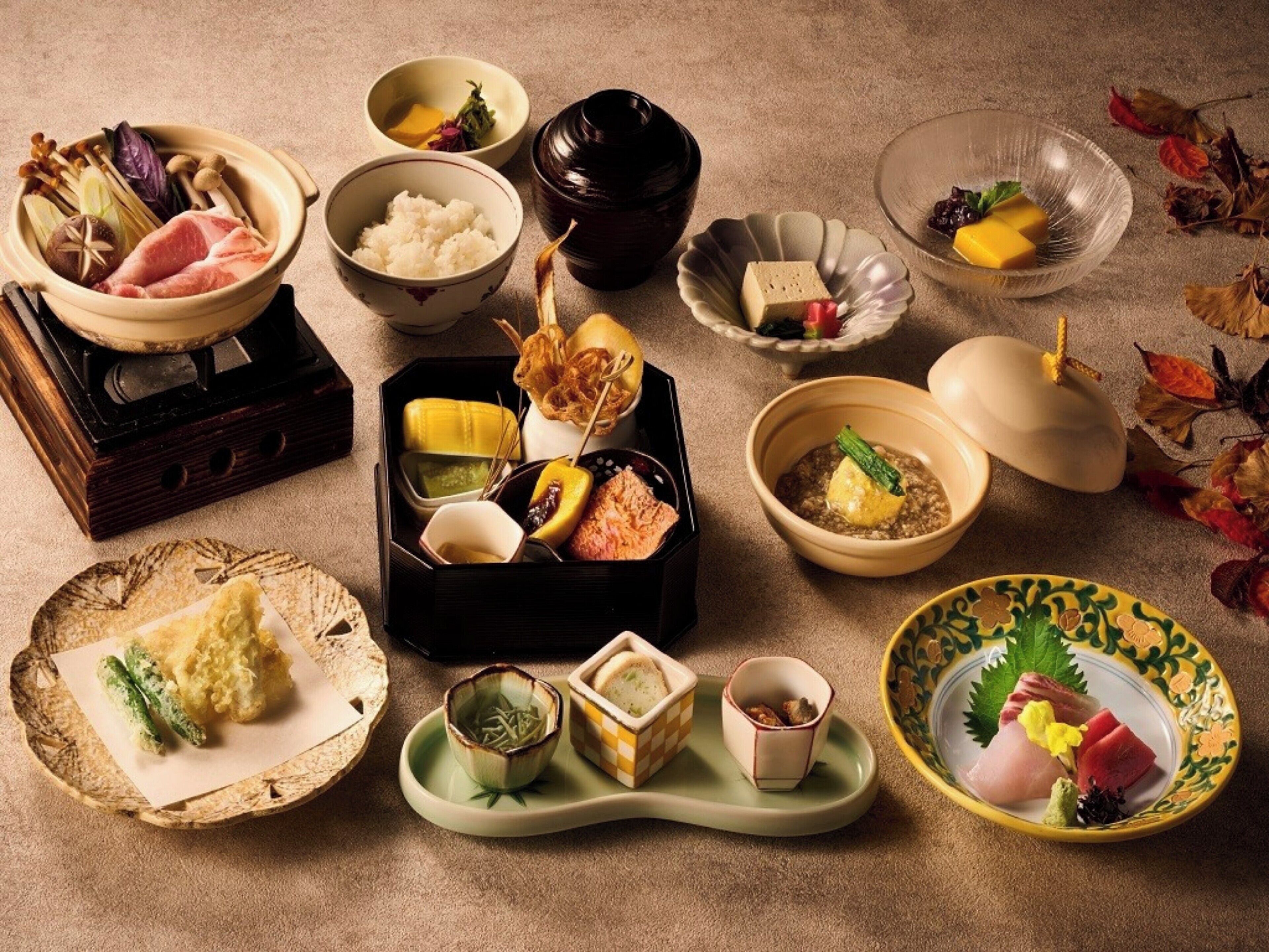 A variety of traditional Japanese dishes arranged on a table, including sushi, rice, and pickled vegetables.