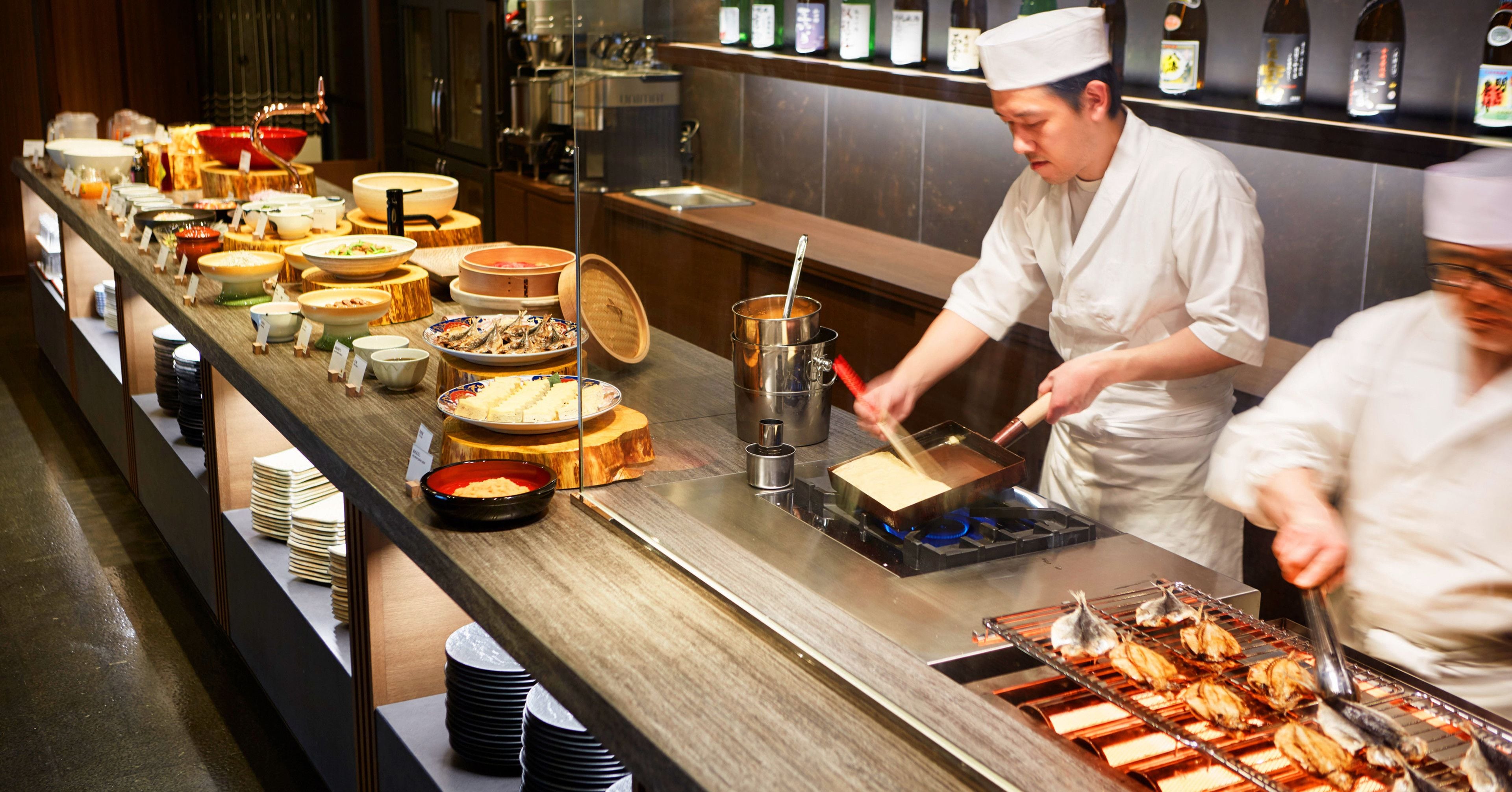 A buffet setup with various dishes and a chef preparing food.