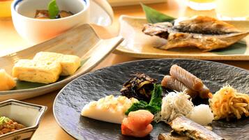 Une variété de plats japonais sont disposés sur la table, notamment du poisson, du tofu et des légumes.
