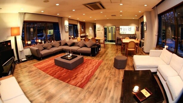 A spacious living room with a sectional sofa, a coffee table, and a dining area with a table and chairs. - Morino Lodge Hakuba (Hakuba)