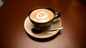 A cup of coffee with latte art on a saucer, placed on a table. - Morino Lodge Hakuba (Hakuba)