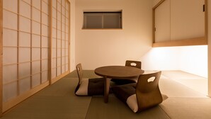 A tatami mat room with a low table and cushions, a sliding door, and a window. - Hotel Grand Vert Kyukaruizawa (Karuizawa)