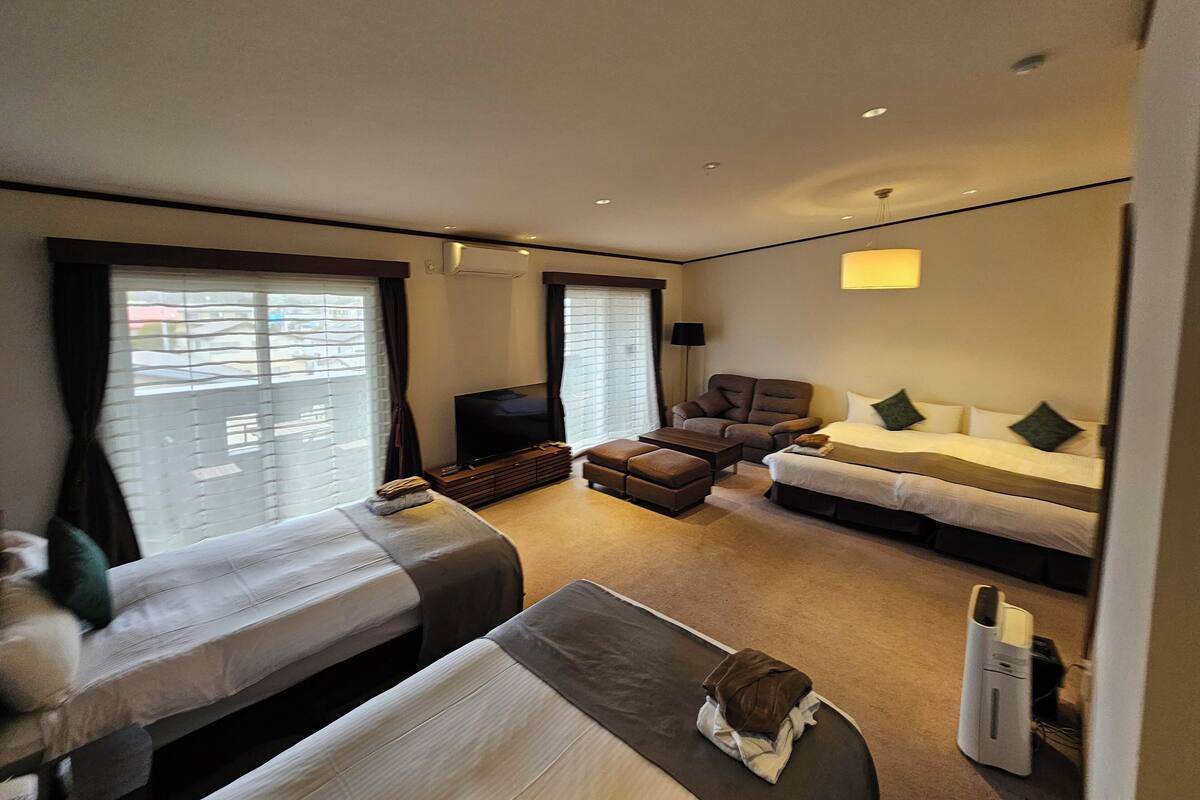 Une chambre d’hôtel avec deux lits, un canapé, une télévision et un bureau.