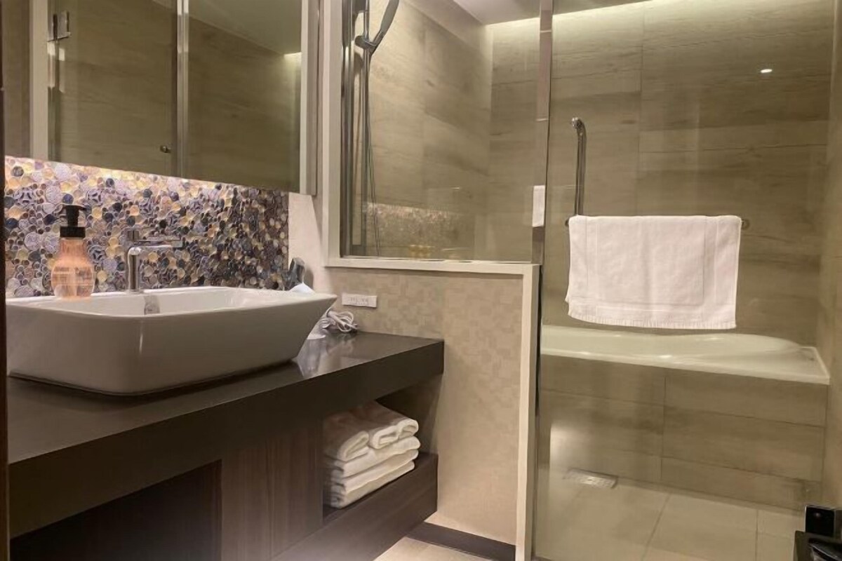 Une salle de bain moderne avec un grand lavabo, une douche en verre et une serviette blanche accrochée au mur.