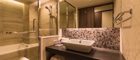 A modern bathroom with a glass-enclosed shower, a large mirror, and a dark countertop with a sink.