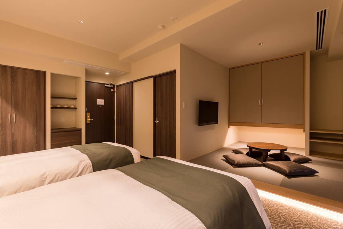 Une chambre d’hôtel avec deux lits, un canapé, une télévision et une armoire.