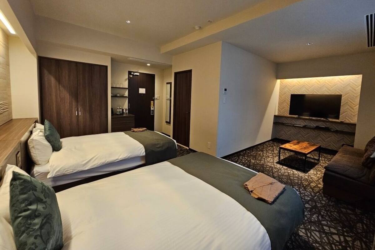 Une chambre d’hôtel avec deux lits, une télévision, une petite table et un canapé.