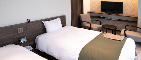 A hotel room with two beds, a TV mounted on the wall, a small table, and a chair.