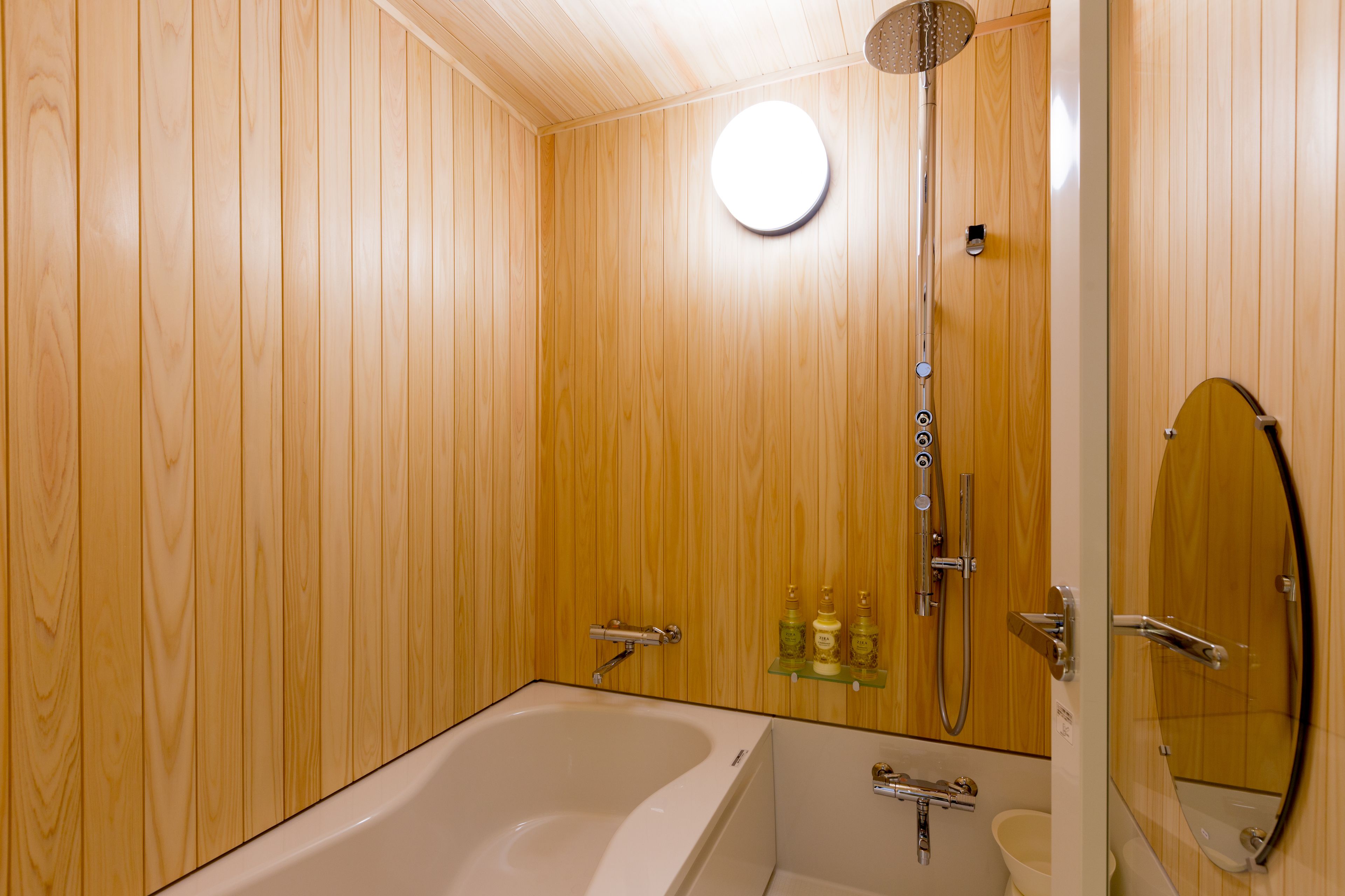 A wooden-paneled bathroom with a bathtub, a shower, and a mirror.