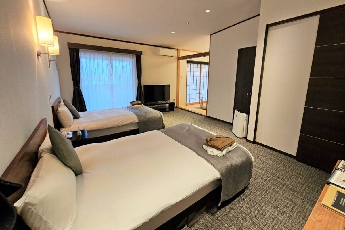 Une chambre d’hôtel avec deux lits, un bureau, une chaise, une télévision et une armoire.
