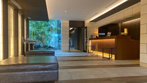 A modern hotel lobby with a reception desk, seating area, and a view of greenery outside. - Hotel Grand Vert Kyukaruizawa (Karuizawa)