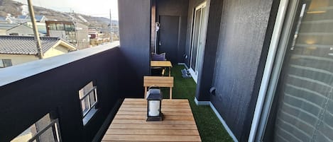 A balcony with a wooden table, a lantern, and a pair of shoes.