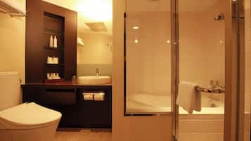 A bathroom with a toilet, a sink, a mirror, and a shower.