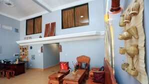 A spacious living room with a fireplace, wooden furniture, and a wall decorated with woven baskets. - Cheng Lay Guesthouse (Siem Reap)