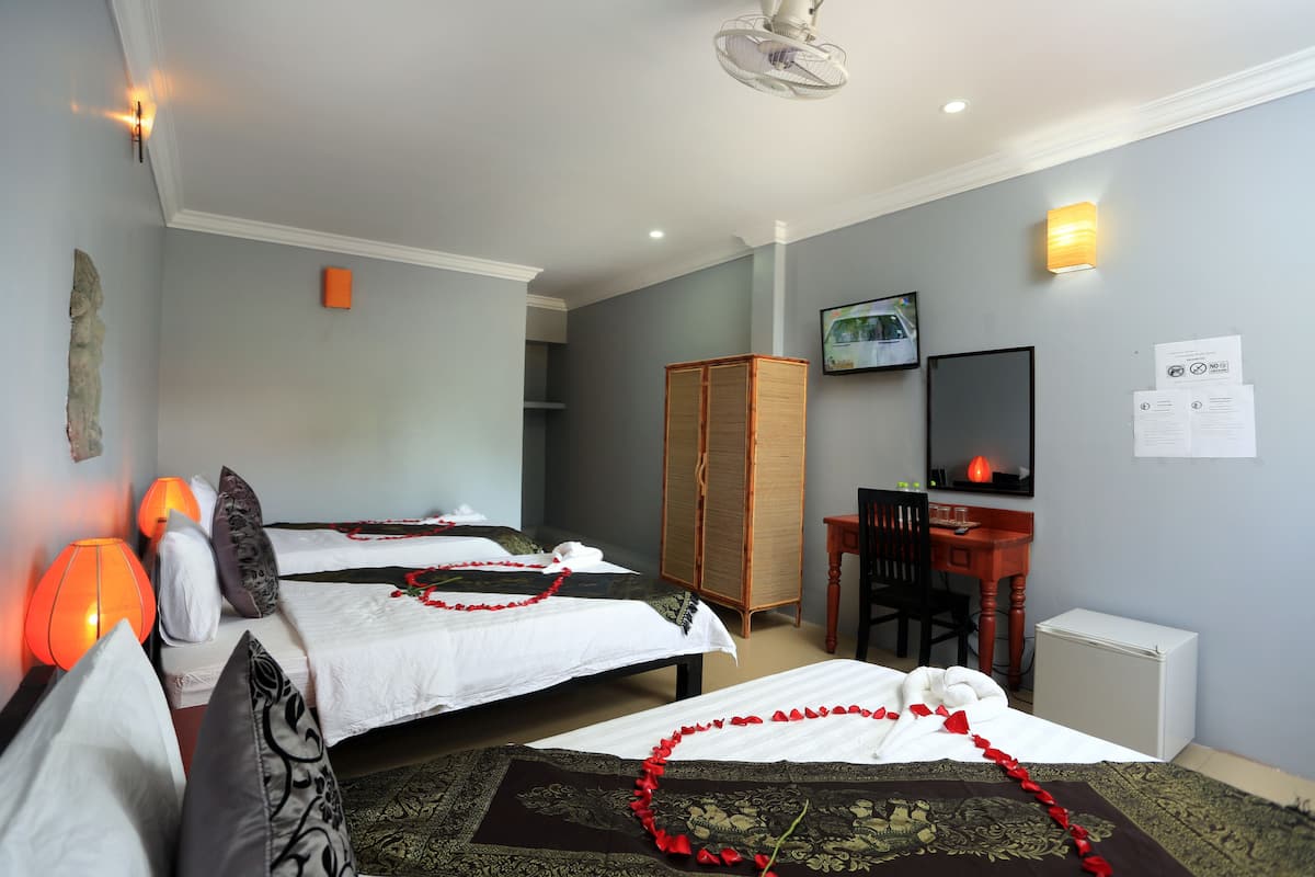 Quarto de hotel com duas camas, uma escrivaninha, uma cadeira, uma televisão e um guarda-roupa.