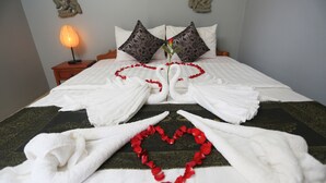 A neatly made bed with white linens, a heart-shaped arrangement of red rose petals, and a single rose in the center. - Cheng Lay Guesthouse (Siem Reap)