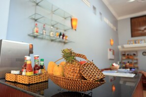 A reception area with a wicker fruit basket on the counter, a glass shelf with bottles, and a wall-mounted clock. - Cheng Lay Guesthouse (Siem Reap)