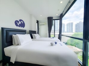 Habitación de hotel con dos camas, un ventanal grande y vistas a rascacielos.