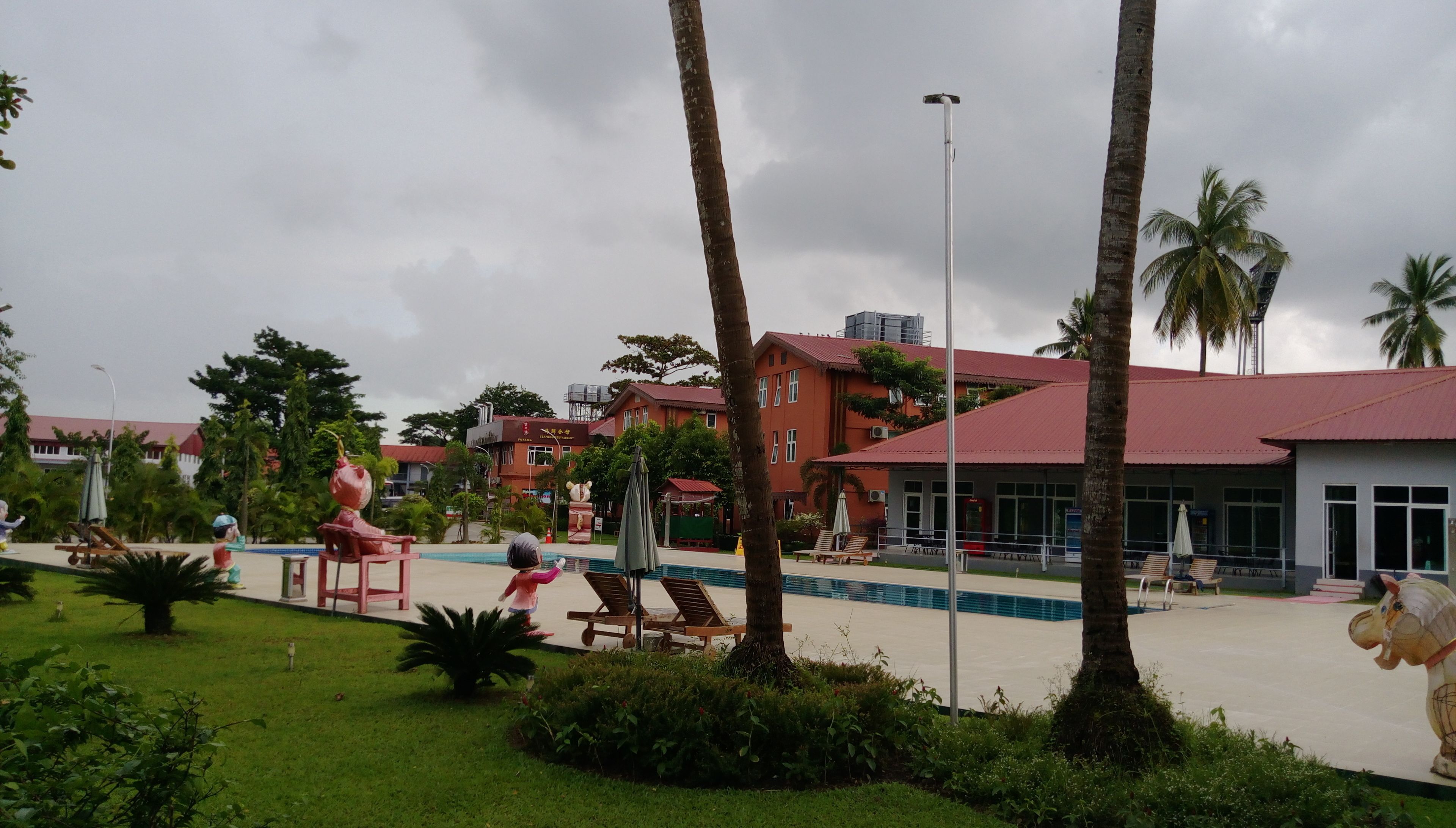 Un resort con piscina, palmeras y un edificio de techo rojo.