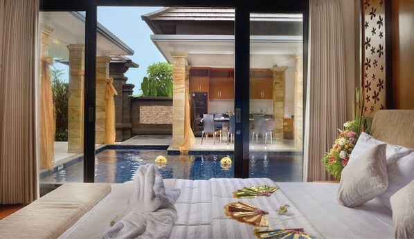 A bedroom with a view of a swimming pool, a dining area, and a kitchen.