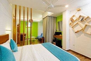Habitación de hotel con cama, escritorio, silla y una mesita.