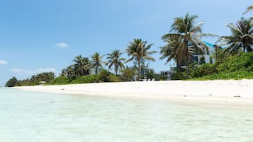 Aan het strand, wit zand, ligstoelen aan het strand, parasols